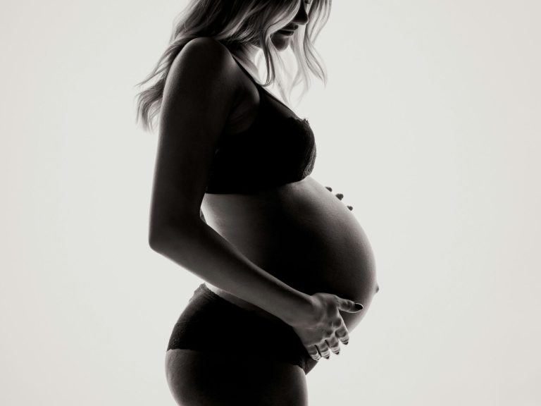 Silhouette of a pregnant woman gently cradling her belly.
