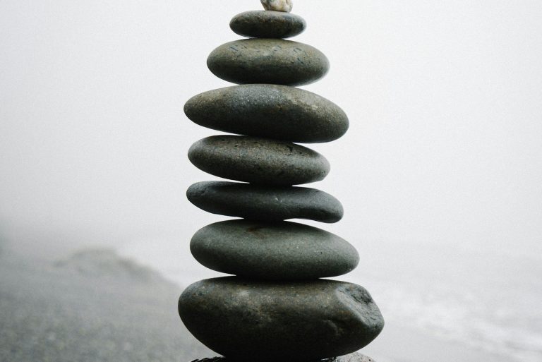 A stack of smooth, gray stones balanced on top of each other against a misty background.