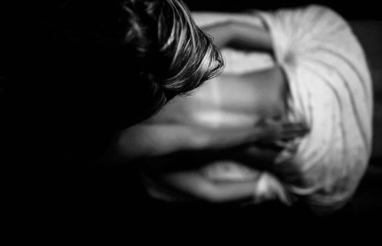 A black and white photo of a massage therapist massaging down the back of a client.