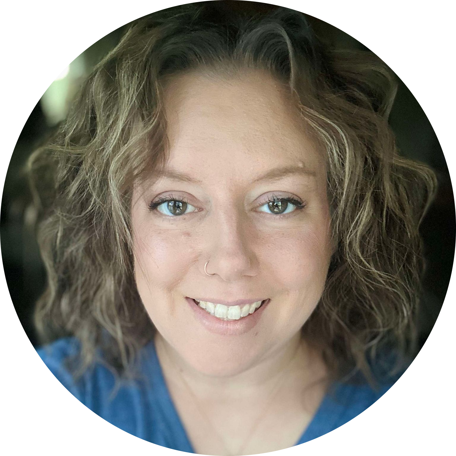 Smiling woman, the massage therapist, with curly hair wearing a blue shirt, framed in a circular design.