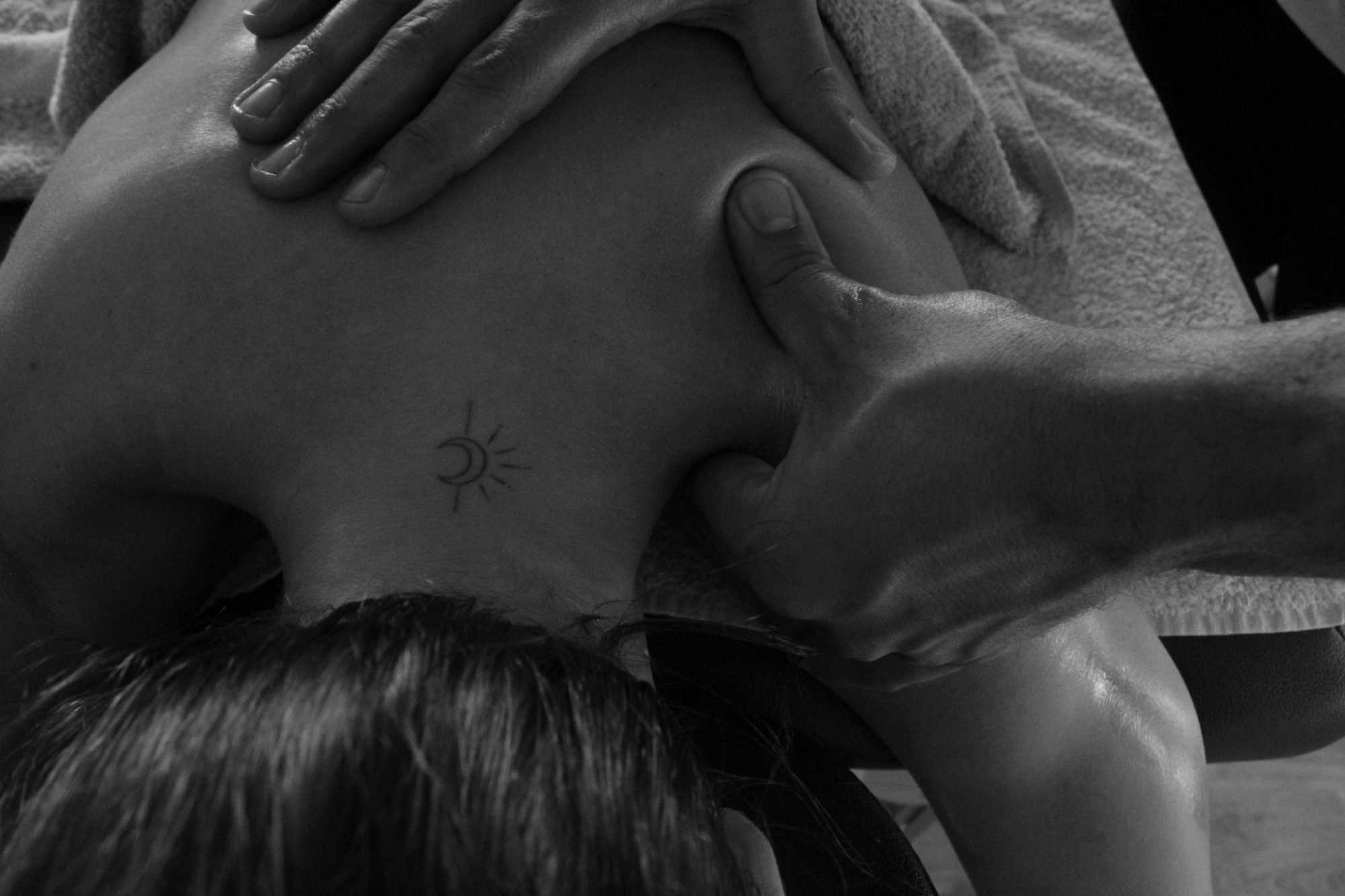 A person receiving a massage, focused on the back and hands applying pressure.